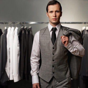 Businessman in classic vest against row of suits in shop